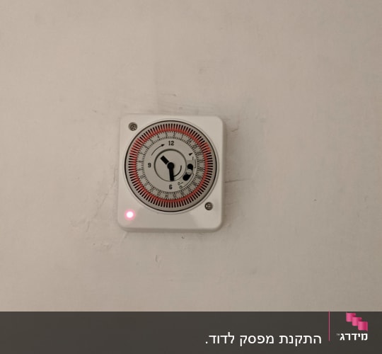 טיימר חשמלי על קיר עם נורית אדומה דולקת